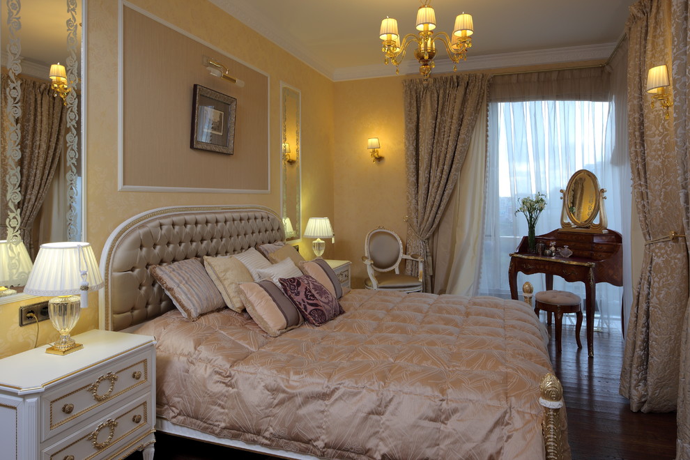This is an example of a traditional master bedroom in Moscow with yellow walls and dark hardwood floors.