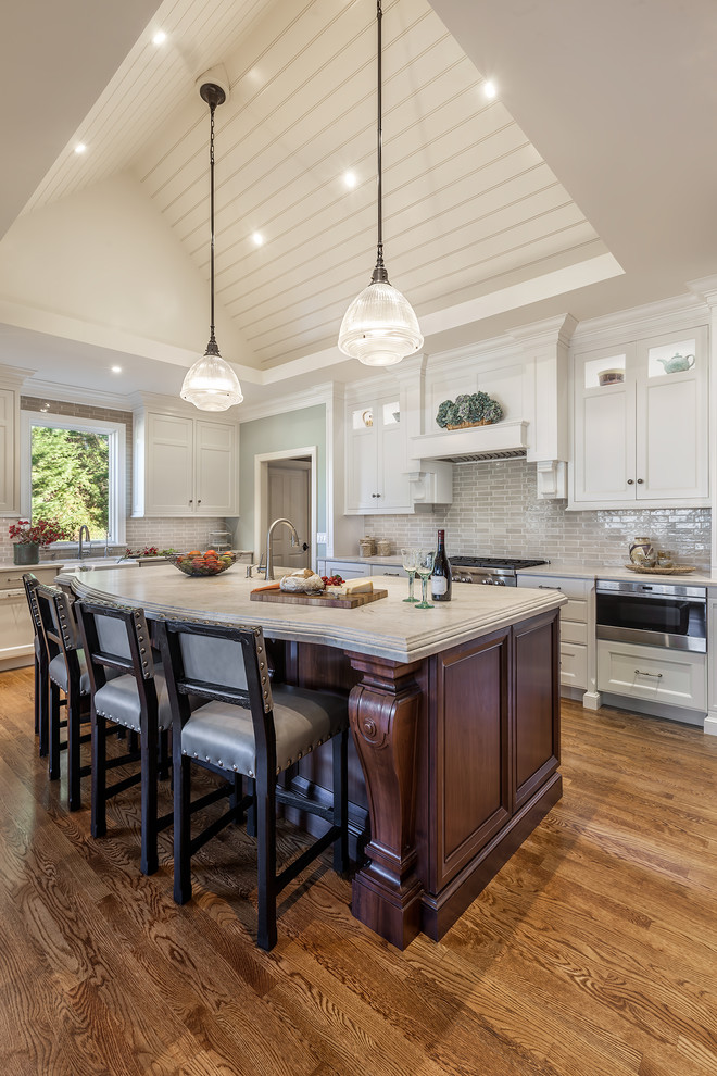 This is an example of a large traditional kitchen in Other with white cabinets, granite benchtops, medium hardwood floors, with island, recessed-panel cabinets, grey splashback and stainless steel appliances.