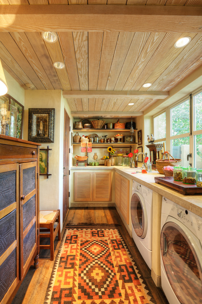 This is an example of a country l-shaped utility room in Sacramento with louvered cabinets and a side-by-side washer and dryer.