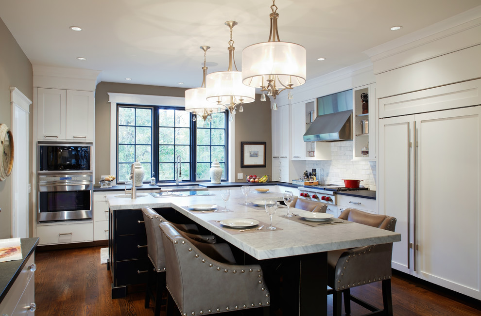 Design ideas for a large traditional l-shaped separate kitchen in Philadelphia with subway tile splashback, panelled appliances, a farmhouse sink, shaker cabinets, white cabinets, marble benchtops, white splashback, dark hardwood floors and with island.