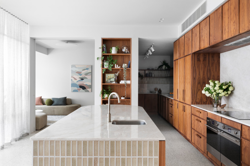 Cette image montre une grande cuisine parallèle design en bois foncé avec un électroménager en acier inoxydable, un sol en terrazzo et îlot.