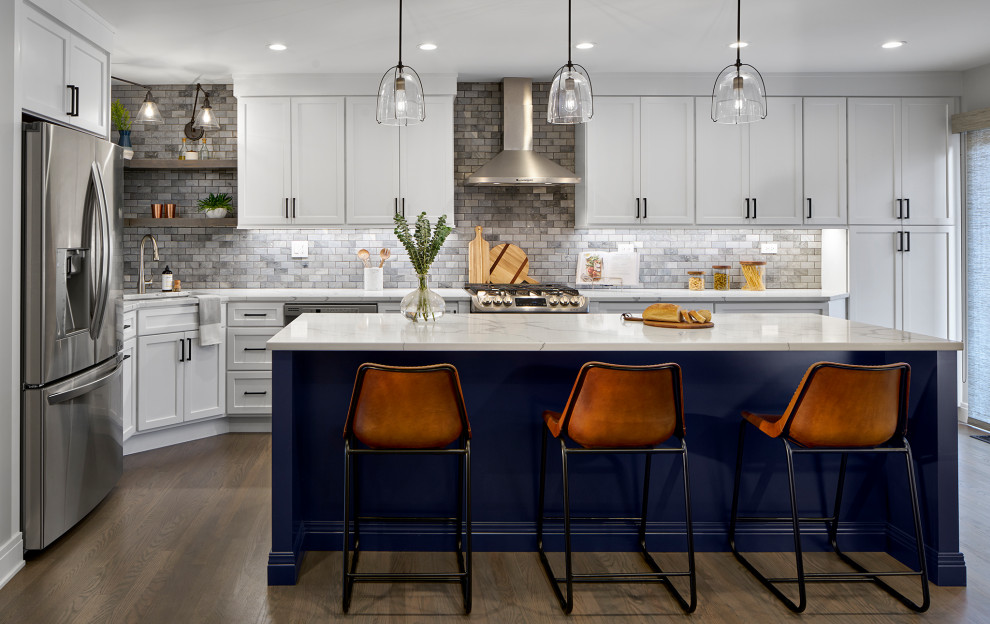 Large transitional l-shaped eat-in kitchen in Chicago with white cabinets, grey splashback, marble splashback, stainless steel appliances, medium hardwood floors, with island, white benchtop, an undermount sink, shaker cabinets, quartz benchtops and brown floor.