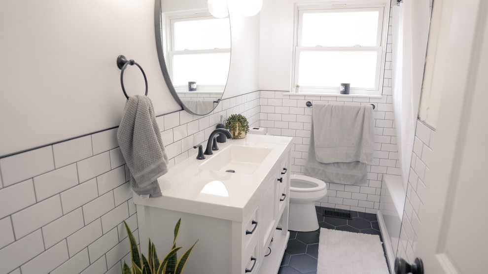 Klassisk inredning av ett litet vit vitt badrum med dusch, med luckor med profilerade fronter, vita skåp, ett fristående badkar, en dusch i en alkov, en toalettstol med hel cisternkåpa, vit kakel, keramikplattor, vita väggar, cementgolv, ett undermonterad handfat, marmorbänkskiva, svart golv och dusch med gångjärnsdörr