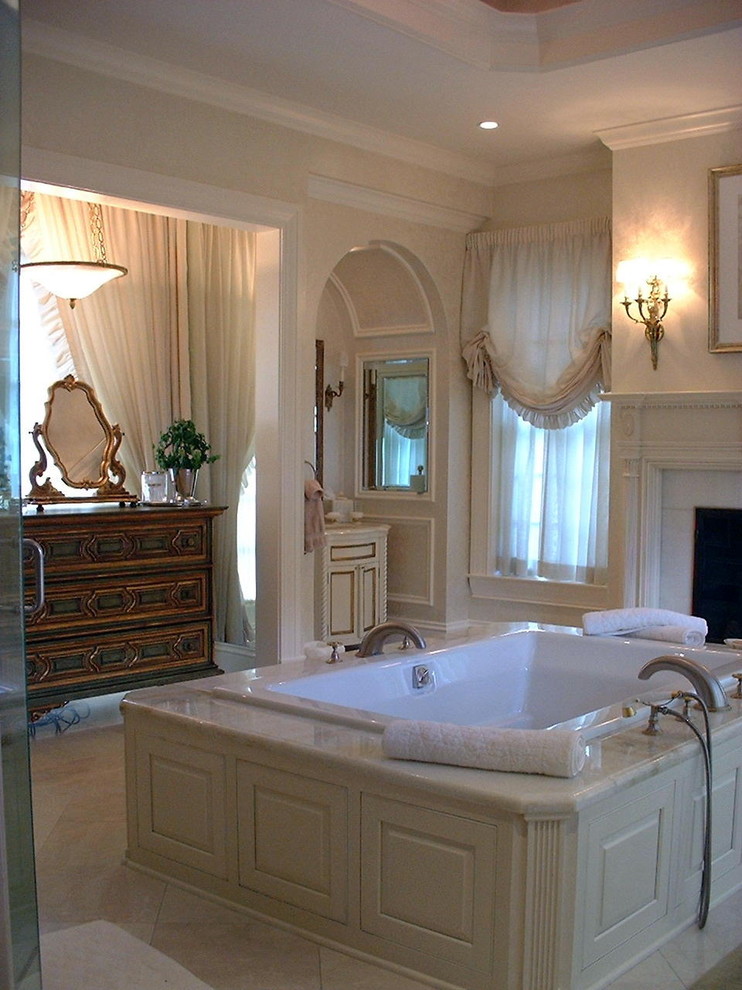 Photo of a large traditional master bathroom in Chicago with raised-panel cabinets, white cabinets, a drop-in tub, beige walls, travertine floors and marble benchtops.