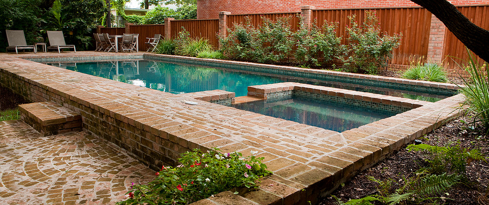 Design ideas for a mid-sized midcentury backyard rectangular lap pool in Austin with brick pavers and a hot tub.