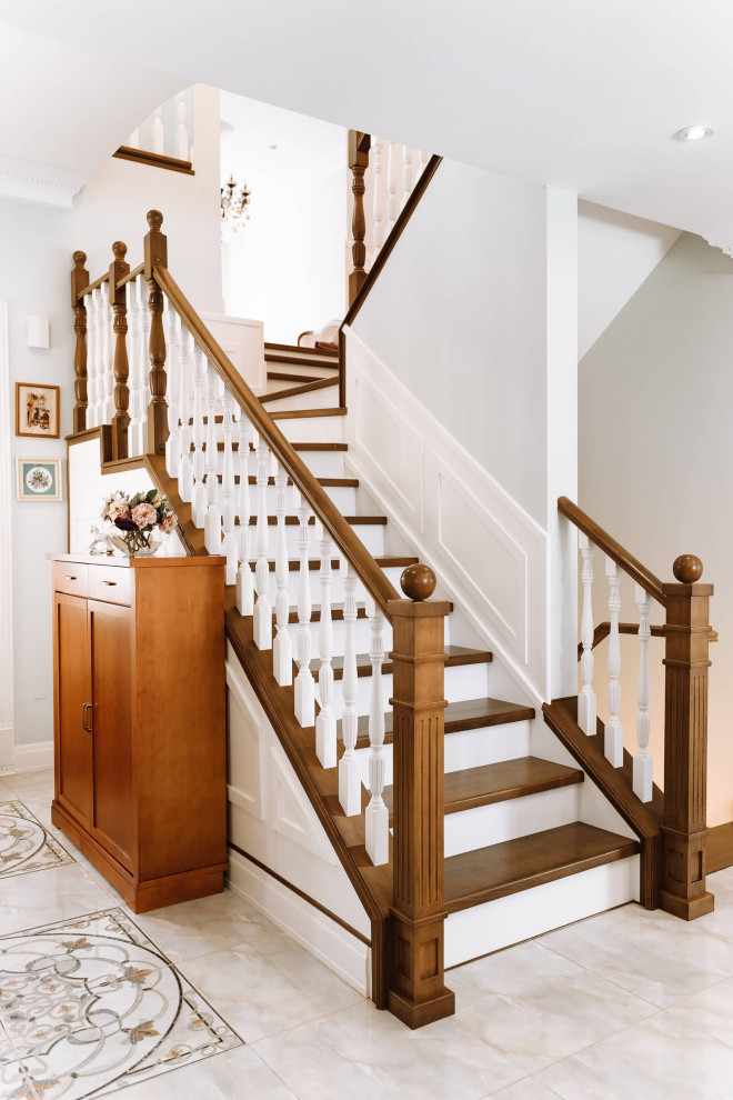 Ejemplo de escalera en U clásica grande con escalones de madera, contrahuellas de madera, barandilla de madera y panelado