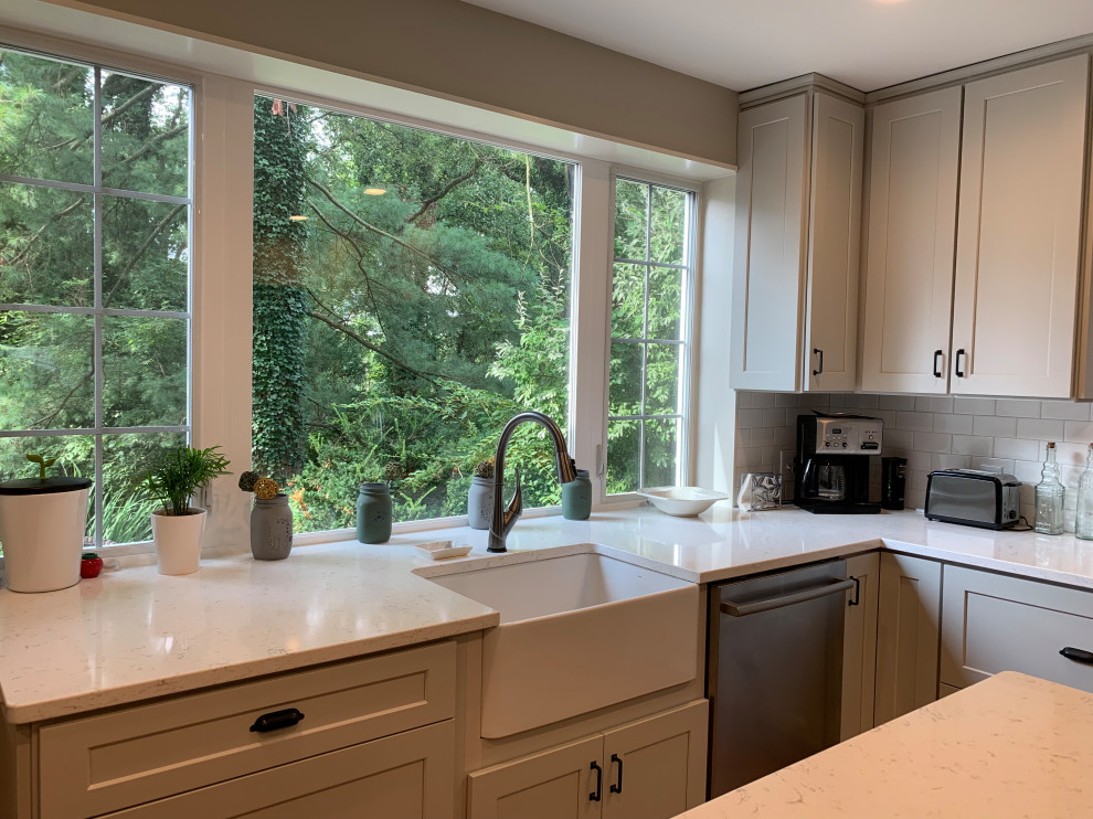Inspiration for a mid-sized transitional l-shaped medium tone wood floor eat-in kitchen remodel in Baltimore with a farmhouse sink, shaker cabinets, gray cabinets, quartz countertops, white backsplash, subway tile backsplash, stainless steel appliances, an island and white countertops