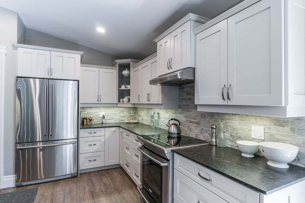 Inspiration for a large arts and crafts l-shaped open plan kitchen in Toronto with an undermount sink, shaker cabinets, white cabinets, granite benchtops, grey splashback, stone tile splashback, stainless steel appliances, dark hardwood floors and with island.