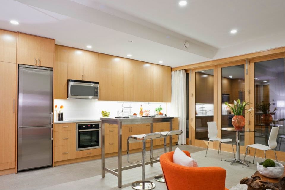 Mid-sized transitional galley porcelain tile kitchen photo in Vancouver with flat-panel cabinets, medium tone wood cabinets, stainless steel appliances, an island and a drop-in sink
