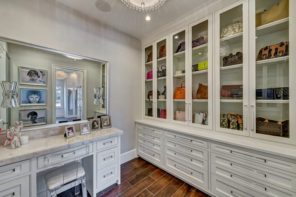 Photo of a large transitional women's walk-in wardrobe in Orange County with glass-front cabinets, white cabinets, ceramic floors and brown floor.