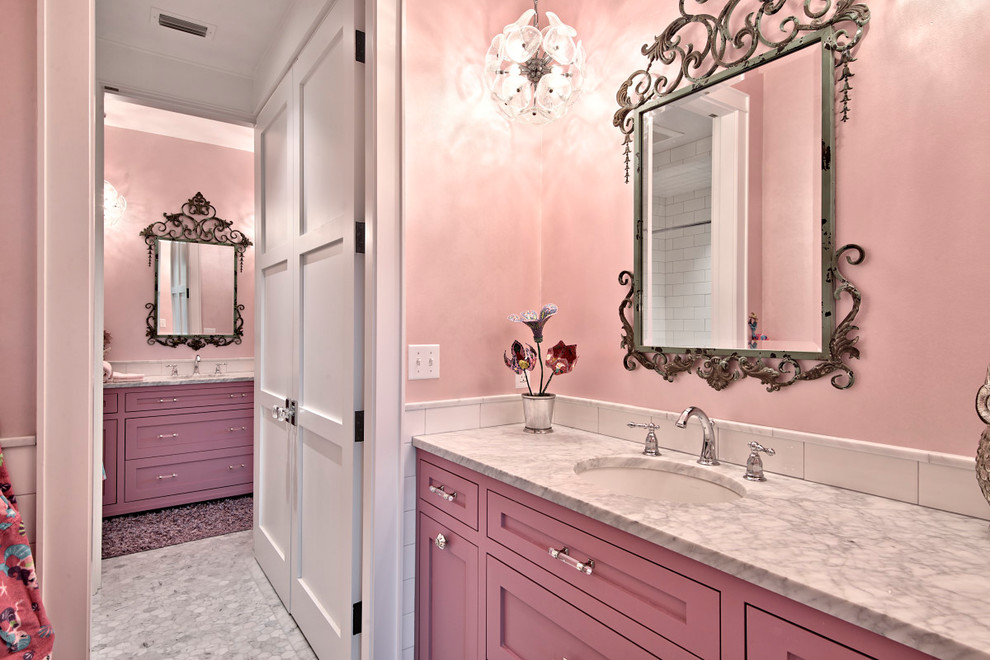 This is an example of an expansive country kids bathroom in Austin with recessed-panel cabinets, purple cabinets, an alcove tub, an open shower, a one-piece toilet, multi-coloured tile, stone tile, pink walls, marble floors, an undermount sink and marble benchtops.