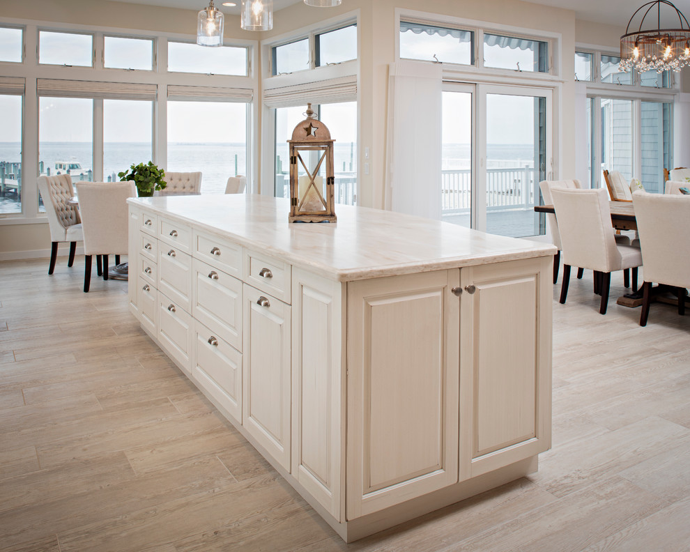 Mid-sized beach style galley porcelain tile open concept kitchen photo with solid surface countertops, an island, raised-panel cabinets, white cabinets, multicolored backsplash, mosaic tile backsplash, stainless steel appliances and an undermount sink
