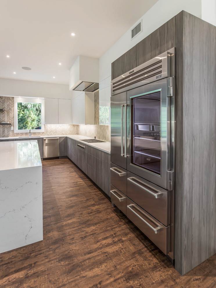 Inspiration for a large contemporary l-shaped open plan kitchen in Jacksonville with an undermount sink, flat-panel cabinets, quartz benchtops, stainless steel appliances, with island, brown floor, white benchtop, medium wood cabinets, beige splashback, mosaic tile splashback and vinyl floors.