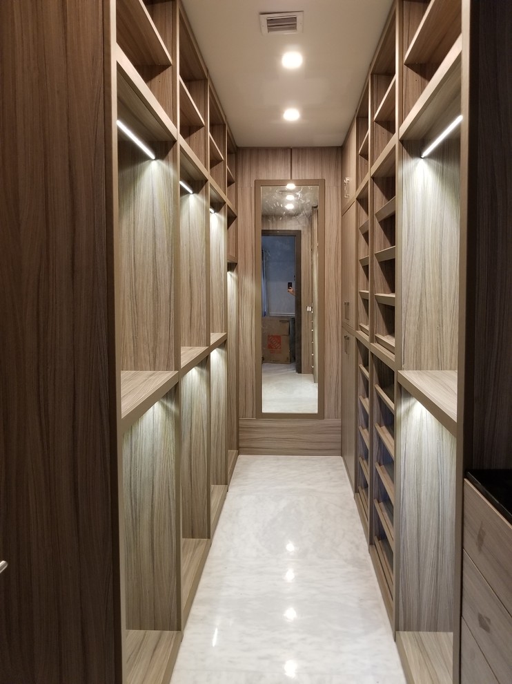 This is an example of a large transitional gender-neutral walk-in wardrobe in Miami with open cabinets, light wood cabinets, marble floors and white floor.