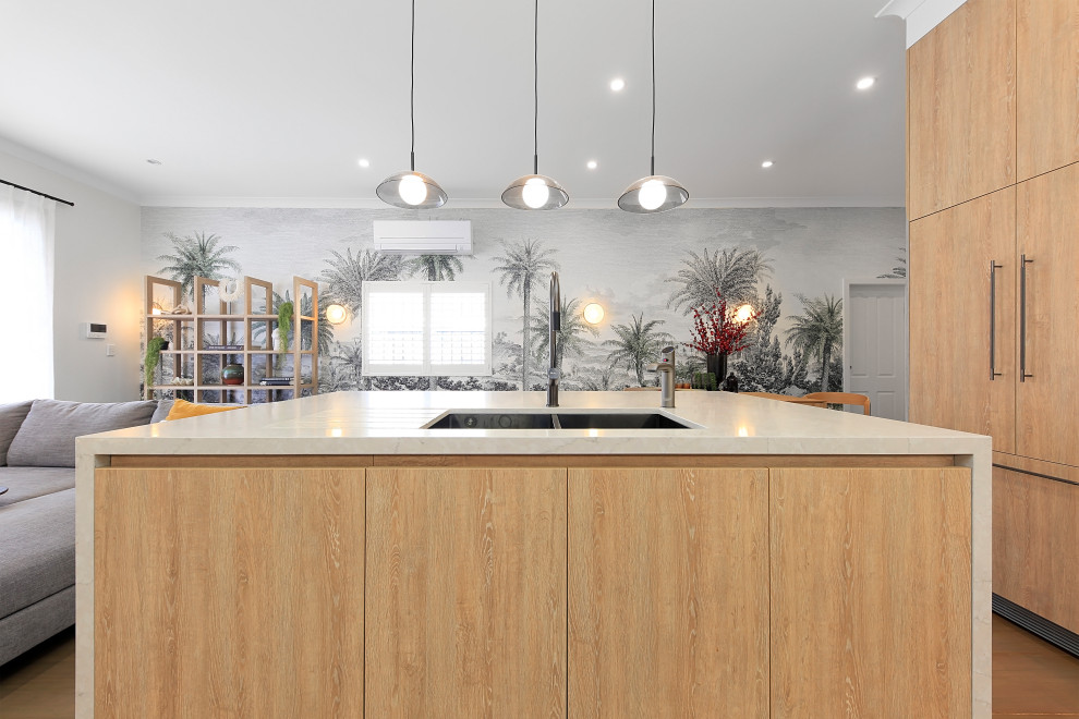 Small contemporary l-shaped open plan kitchen in Sydney with a built-in sink, flat-panel cabinets, light wood cabinets, engineered stone countertops, grey splashback, stone slab splashback, black appliances, light hardwood flooring, an island, brown floors and grey worktops.