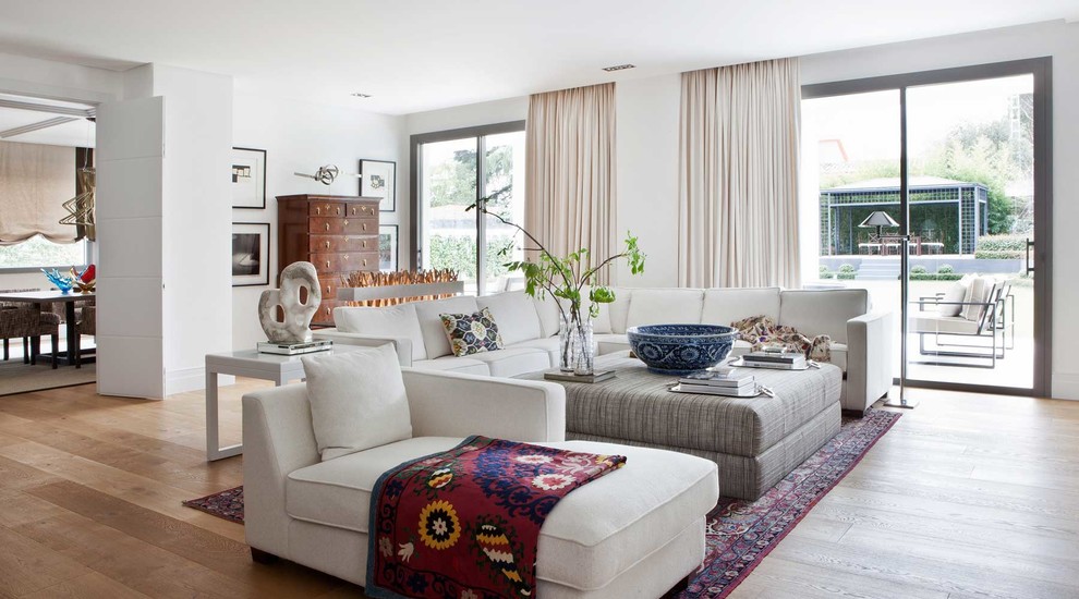 Inspiration for a large transitional open concept living room in Madrid with white walls and medium hardwood floors.