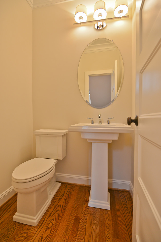 Arts and crafts powder room in DC Metro with a pedestal sink, a two-piece toilet and medium hardwood floors.