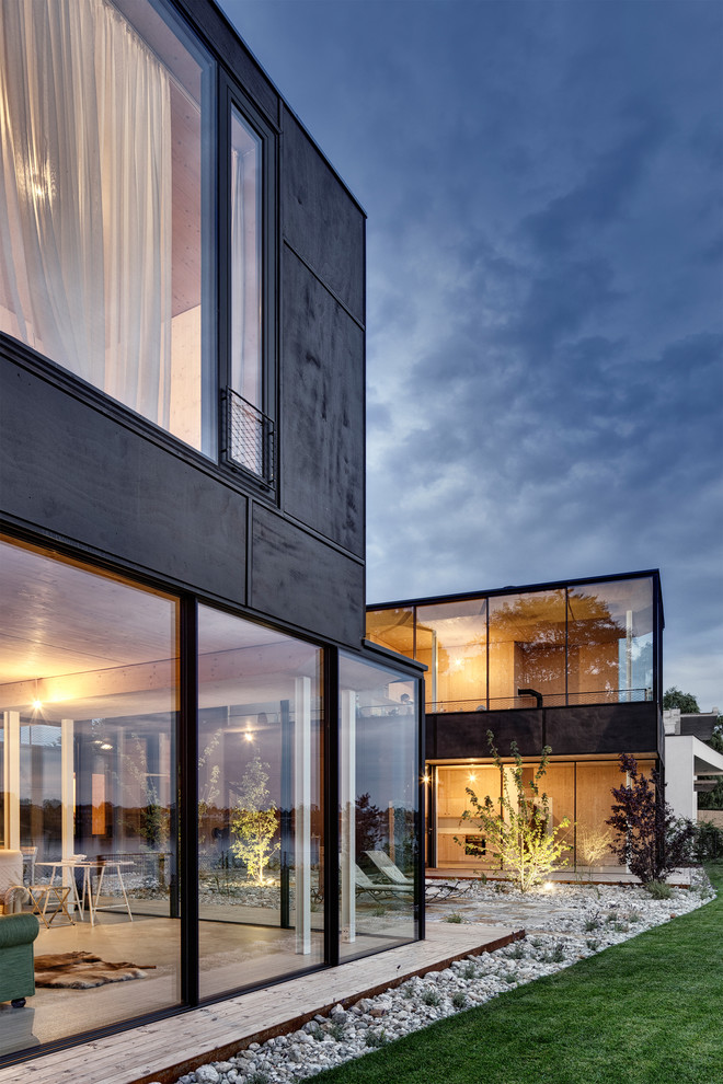 Inspiration for a contemporary two-storey black exterior in Other with a flat roof.
