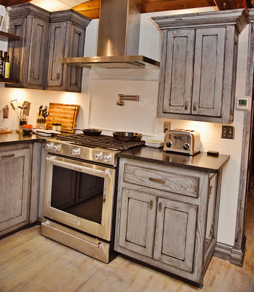 Eat-in kitchen - mid-sized craftsman u-shaped light wood floor and white floor eat-in kitchen idea with a farmhouse sink, recessed-panel cabinets, gray cabinets, granite countertops, white backsplash, cement tile backsplash, stainless steel appliances and an island
