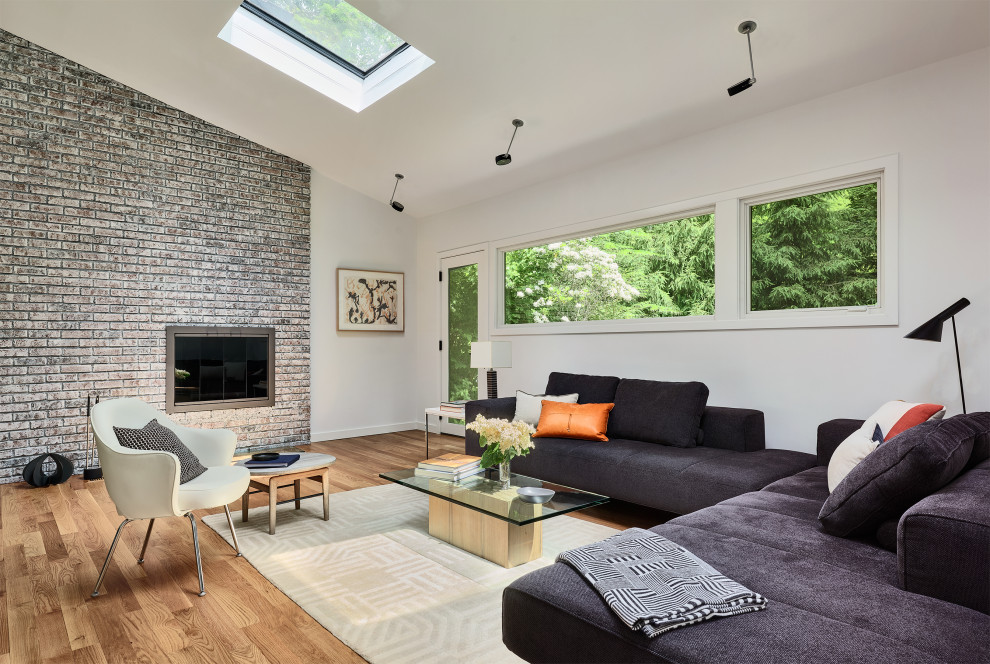 This is an example of a mid-sized modern open concept living room in New York with white walls, medium hardwood floors, a ribbon fireplace, a brick fireplace surround and no tv.