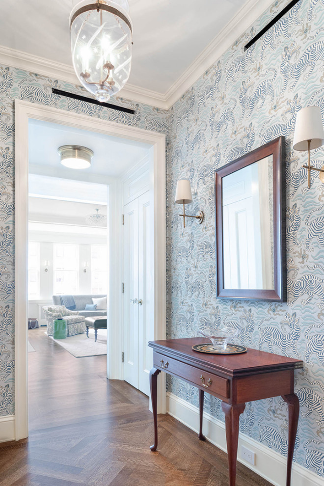 Design ideas for a small transitional foyer in New York with blue walls, medium hardwood floors and wallpaper.