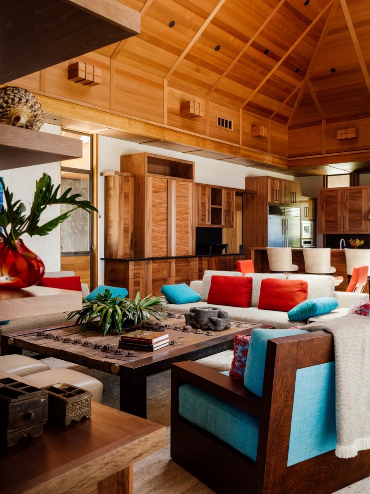 Tropical open concept living room in Hawaii with white walls, dark hardwood floors and brown floor.