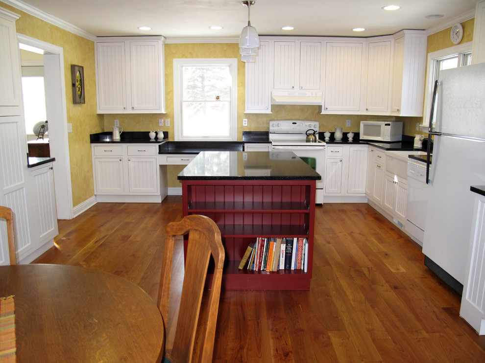 This is an example of a mid-sized country l-shaped eat-in kitchen in Milwaukee with a farmhouse sink, beaded inset cabinets, white cabinets, granite benchtops, yellow splashback, white appliances, medium hardwood floors and with island.