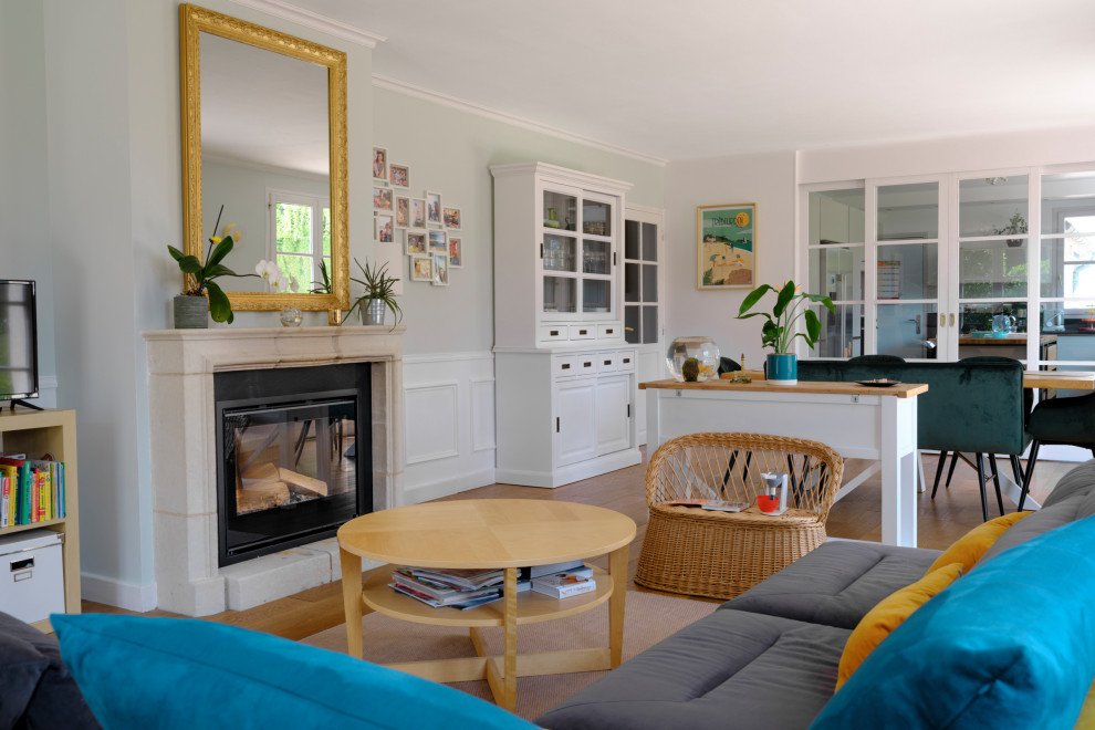 Inspiration for a mid-sized beach style dining room in Other with green walls, light hardwood floors, a standard fireplace, a stone fireplace surround, yellow floor and wallpaper.