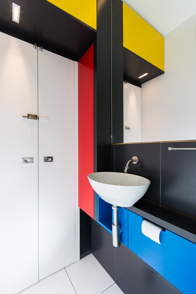 Inspiration for a mid-sized modern powder room in Munich with a wall-mount sink, multi-coloured tile, white tile, flat-panel cabinets, blue cabinets and multi-coloured walls.