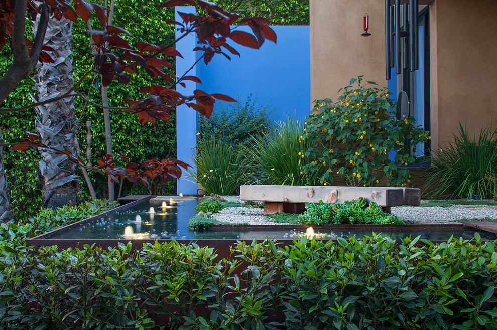 Photo of a contemporary backyard formal garden in Los Angeles with a water feature and gravel.