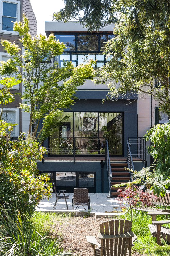 Imagen de fachada de casa multicolor moderna de tamaño medio de tres plantas con revestimiento de estuco, tejado plano y tablilla