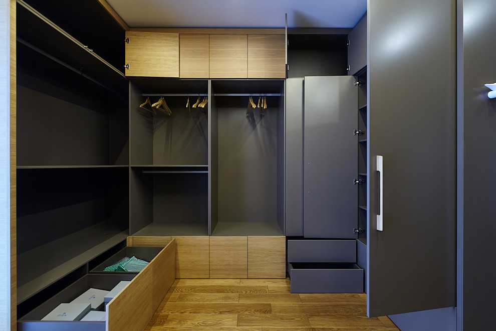 Immagine di una grande cabina armadio unisex contemporanea con ante in legno scuro, pavimento in laminato e pavimento beige