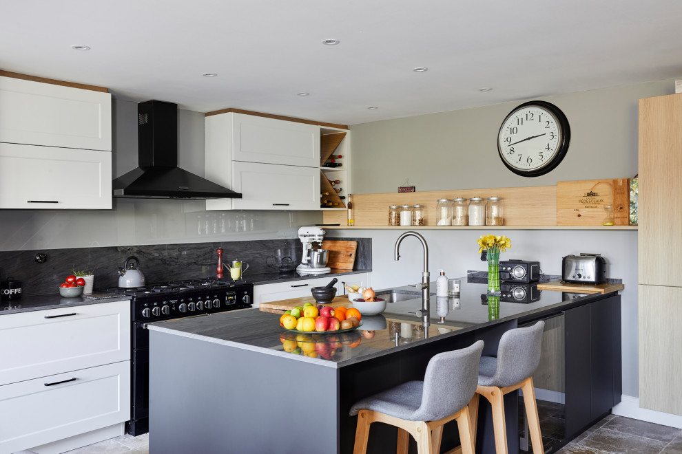 This is an example of a mid-sized transitional single-wall eat-in kitchen in London with shaker cabinets, white cabinets, quartz benchtops, grey splashback, stone slab splashback, with island and grey benchtop.