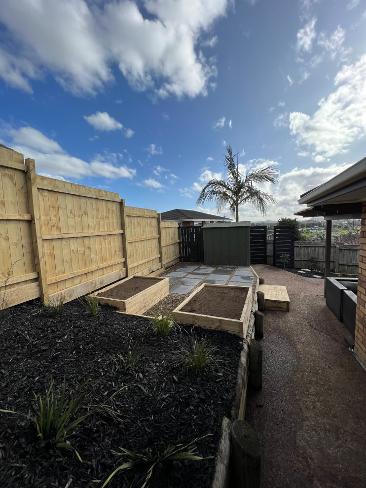 Immagine di un piccolo giardino tropicale dietro casa in primavera con pacciame e recinzione in legno