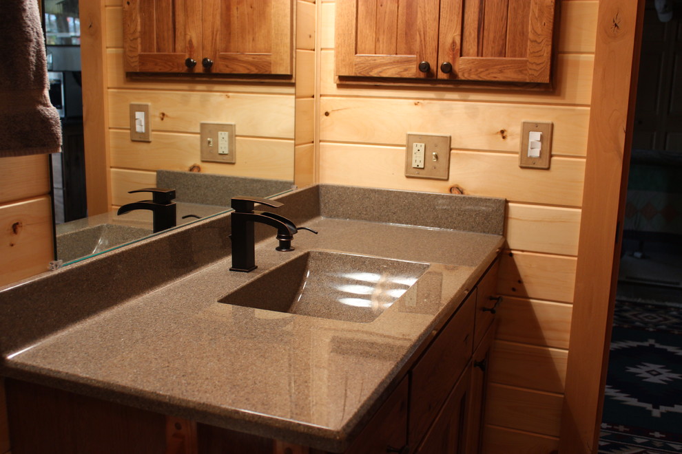 Example of a mid-sized mountain style bathroom design with shaker cabinets, medium tone wood cabinets, beige walls, an integrated sink and granite countertops
