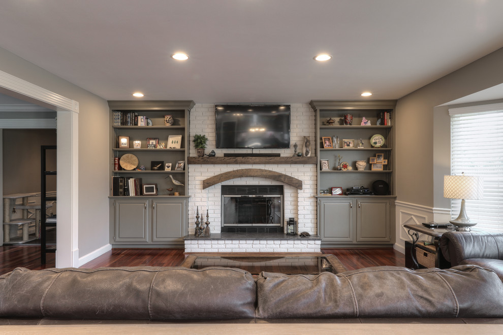 Photo of a mid-sized traditional open concept family room in St Louis with grey walls, dark hardwood floors, a standard fireplace, a brick fireplace surround and a wall-mounted tv.