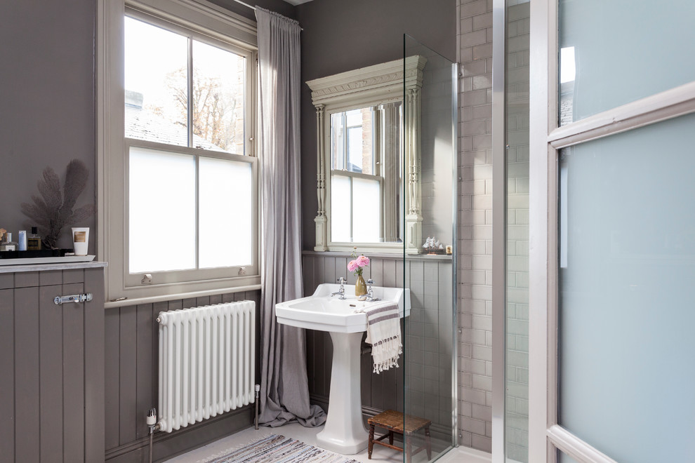 This is an example of a scandinavian bathroom in London with a pedestal sink, a corner shower, gray tile, subway tile and grey walls.