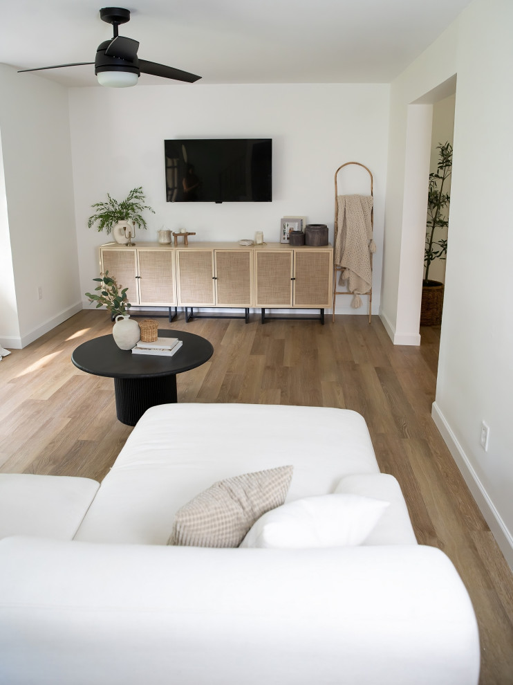 Ispirazione per un soggiorno minimalista di medie dimensioni e chiuso con sala formale, pareti bianche, pavimento in vinile, TV a parete e pavimento marrone