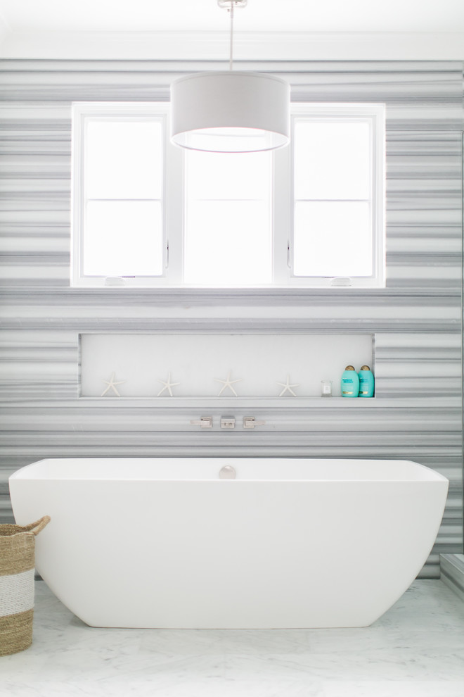 Inspiration for a mid-sized beach style master bathroom in Orange County with a freestanding tub, marble floors, flat-panel cabinets, white cabinets, a corner shower, a one-piece toilet, white tile, ceramic tile, white walls, an undermount sink and engineered quartz benchtops.