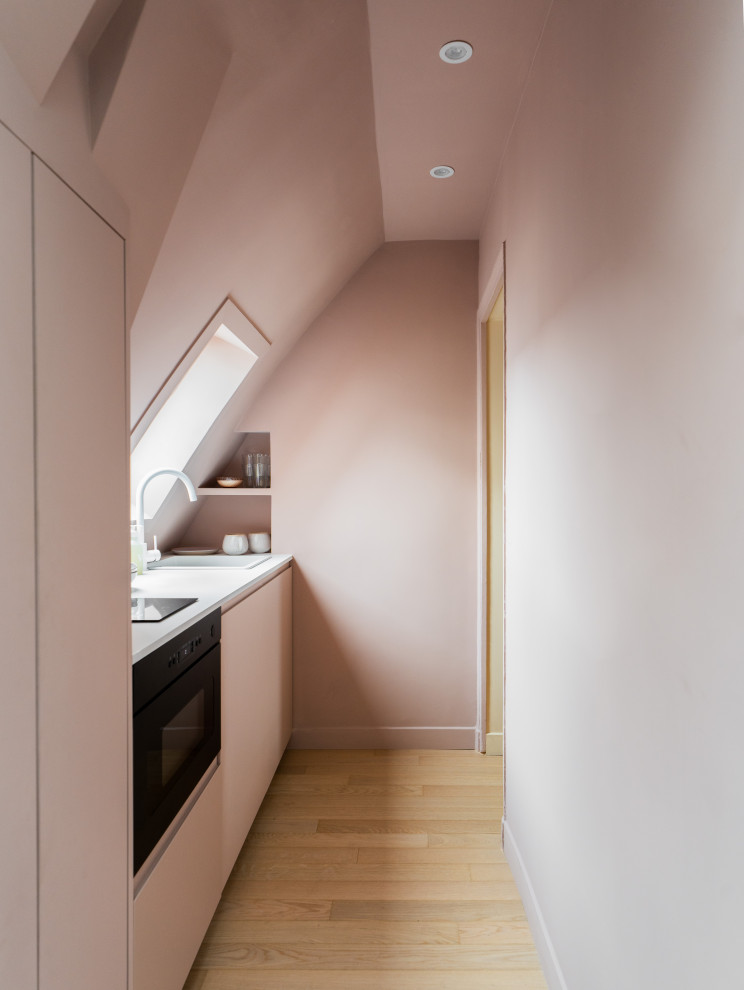 Ispirazione per una piccola cucina lineare minimalista con lavello sottopiano, ante rosa, top in laminato, elettrodomestici da incasso, parquet chiaro, nessuna isola e top bianco
