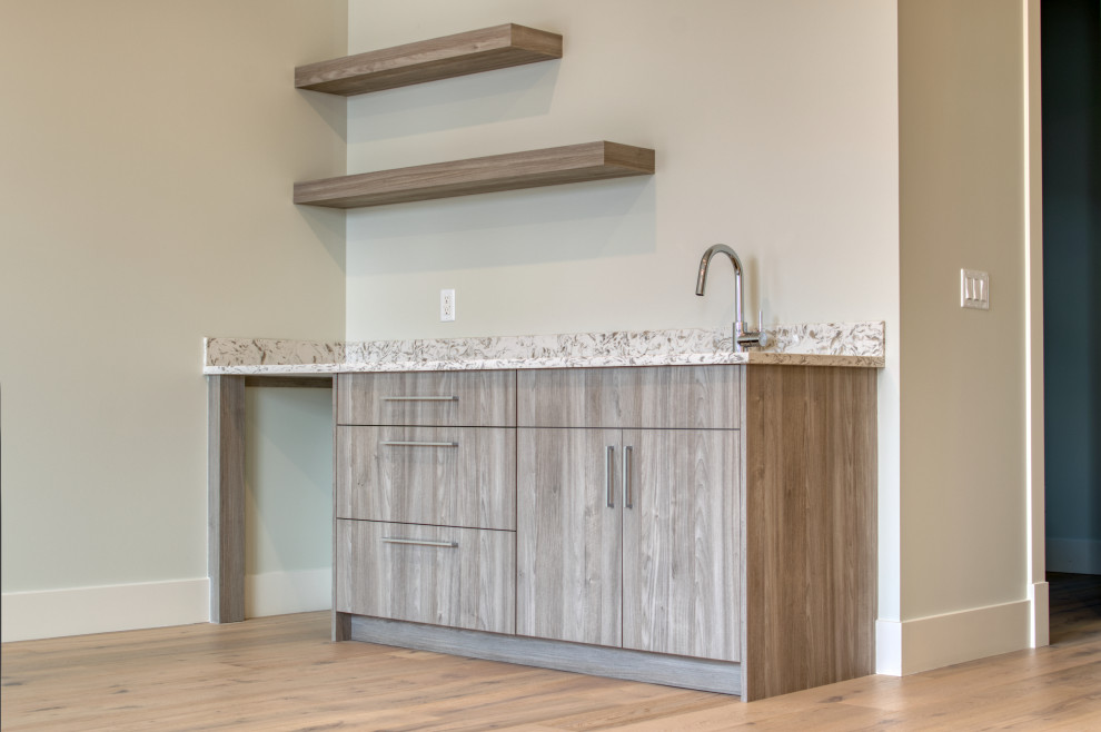 Inspiration for a small traditional single-wall wet bar in Calgary with an undermount sink, flat-panel cabinets, light wood cabinets, granite benchtops, light hardwood floors, beige floor and multi-coloured benchtop.