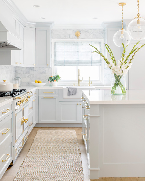 beach style kitchen featuring white and light grey counters with golden hardware