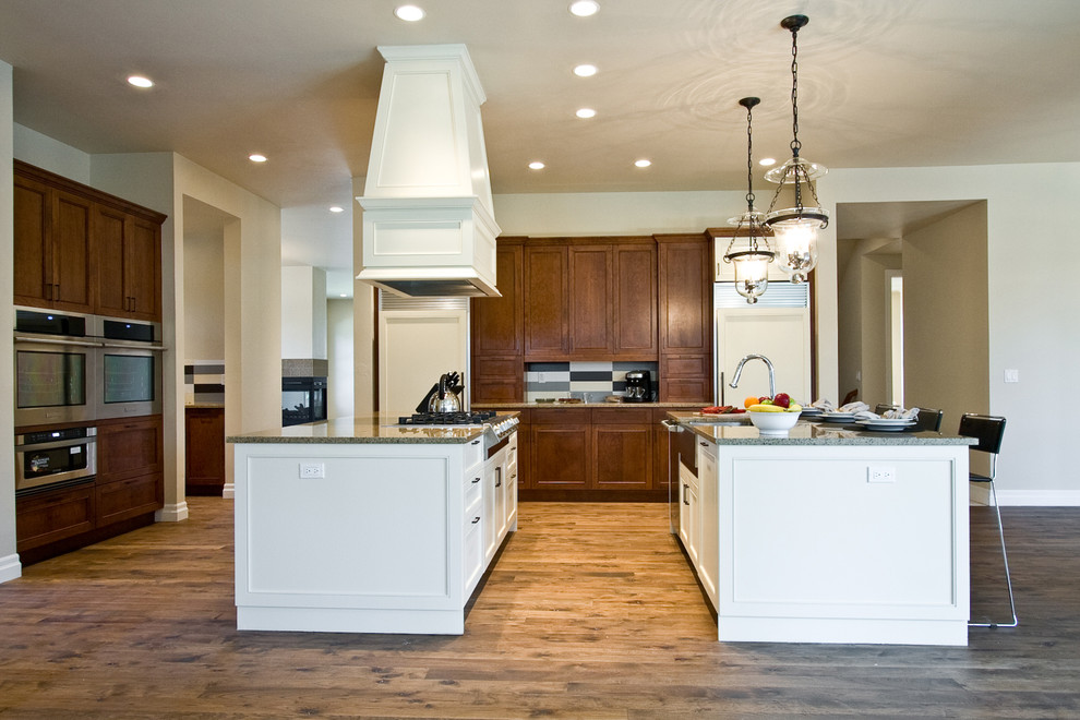 This is an example of a traditional kitchen in Denver with a farmhouse sink, dark wood cabinets and multiple islands.