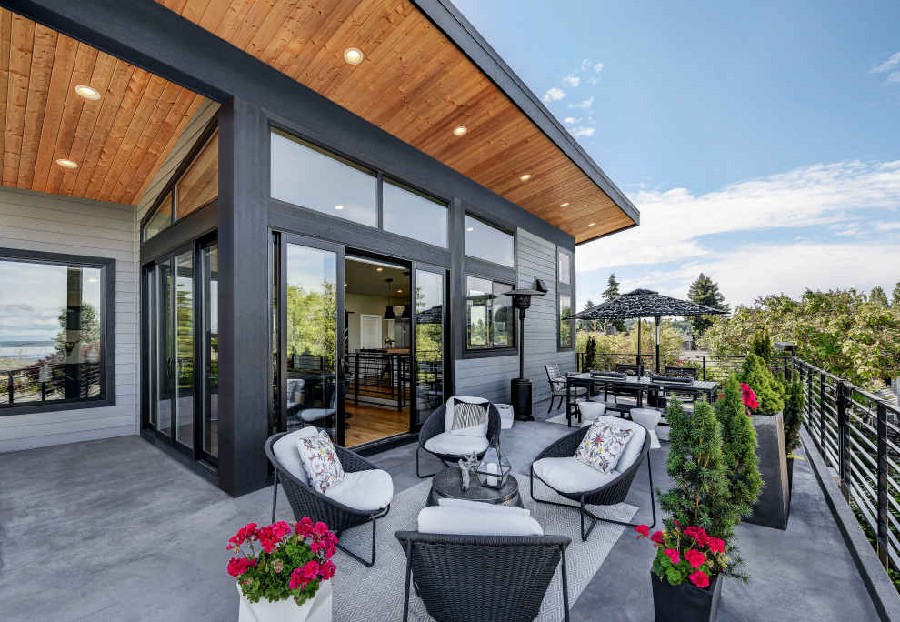 This is an example of a contemporary balcony in Seattle with a roof extension and metal railing.