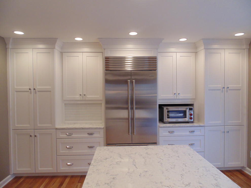 Inspiration for a large transitional u-shaped medium tone wood floor and brown floor eat-in kitchen remodel with an undermount sink, recessed-panel cabinets, white cabinets, quartz countertops, white backsplash, subway tile backsplash, stainless steel appliances, an island and white countertops