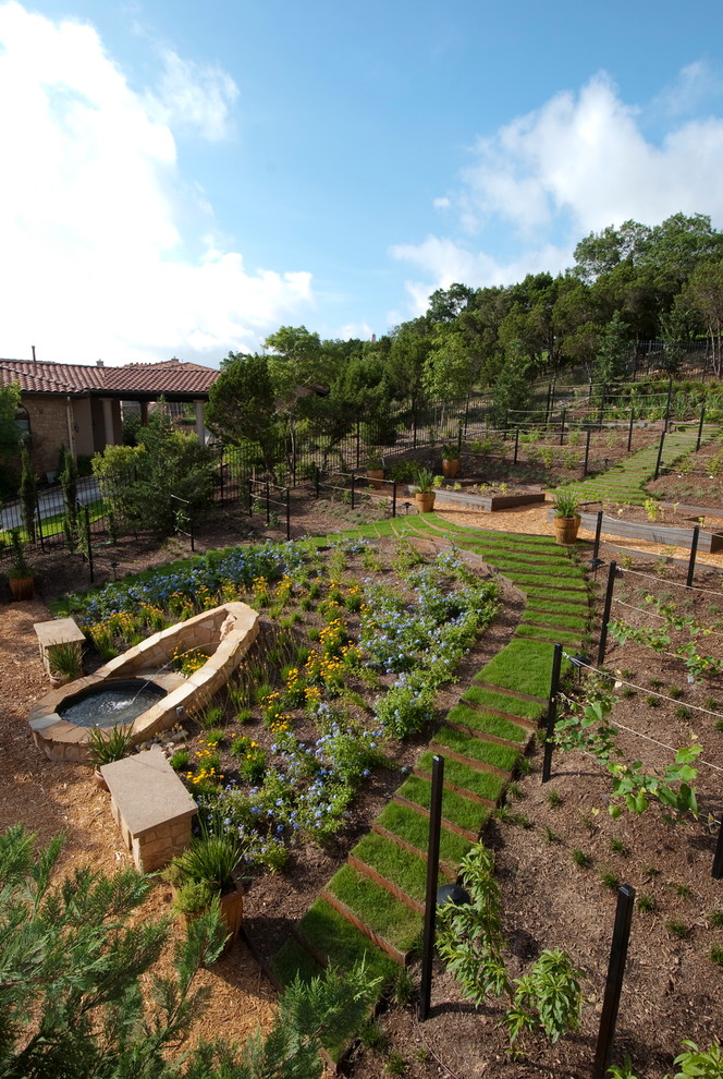 Inspiration for a mediterranean sloped full sun garden in Austin with a water feature.