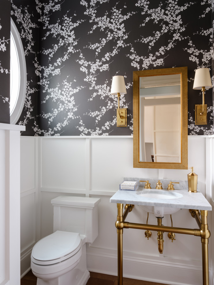 Immagine di un bagno di servizio classico con ante bianche, WC monopezzo, pareti nere, lavabo sospeso, top in marmo, pavimento marrone e boiserie