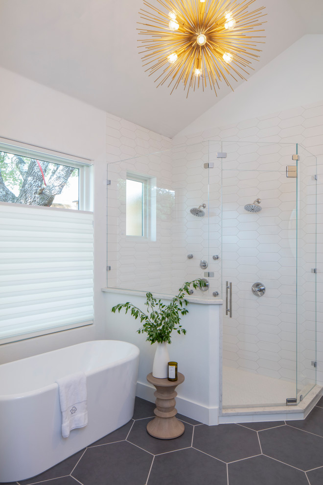 Photo of a mid-sized transitional master bathroom in Austin with a freestanding tub, a corner shower, white tile, white walls, grey floor, a hinged shower door, recessed-panel cabinets, white cabinets, a two-piece toilet, ceramic tile, porcelain floors, an undermount sink, marble benchtops and white benchtops.