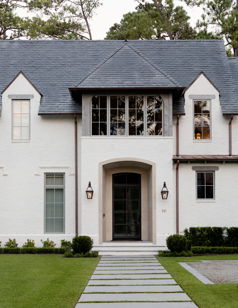 Traditional two-storey brick white house exterior in Houston with a gable roof and a shingle roof.