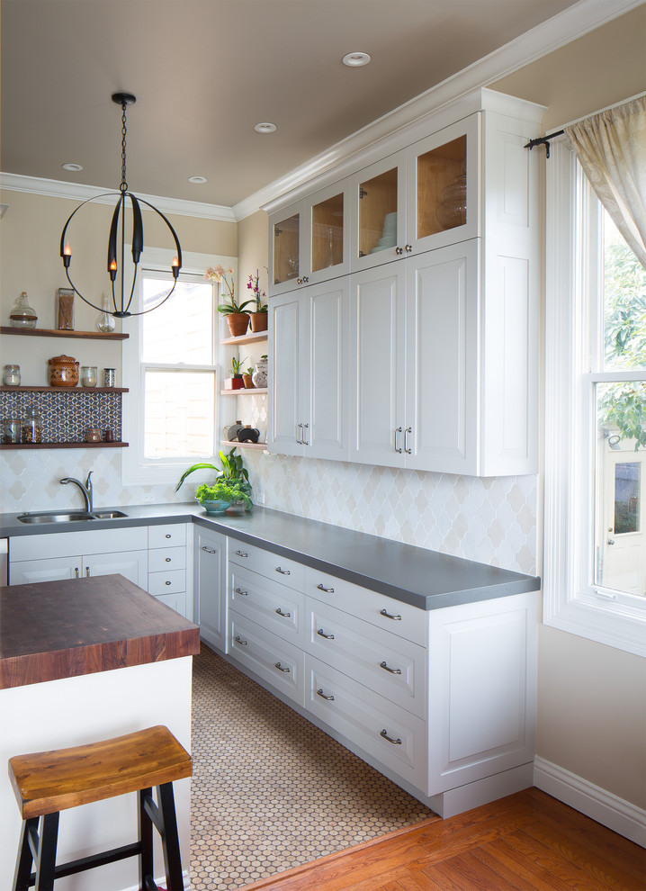 Mid-sized modern l-shaped eat-in kitchen in San Francisco with an undermount sink, white cabinets, quartz benchtops, beige splashback, ceramic splashback, stainless steel appliances, a peninsula and raised-panel cabinets.